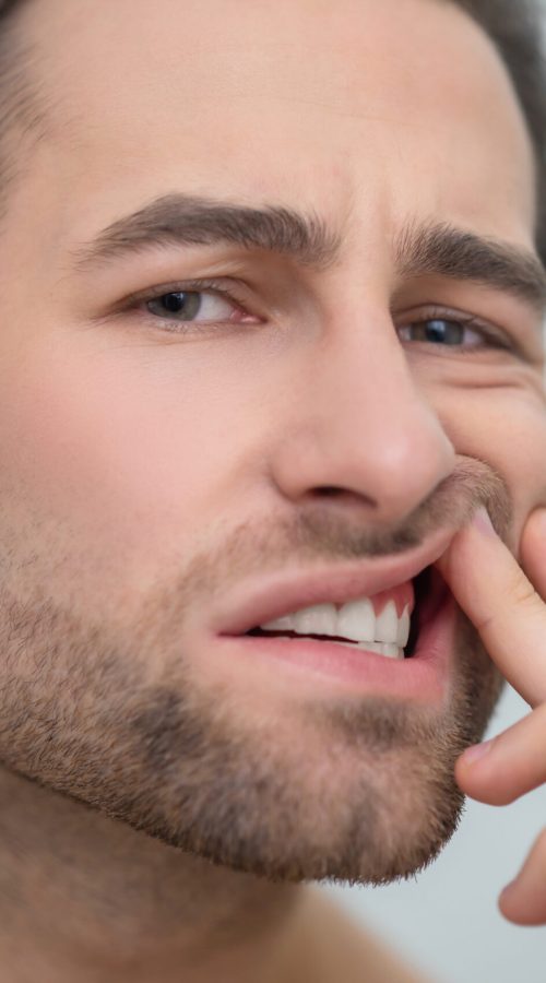 Man checking his teeth and looking disturbed